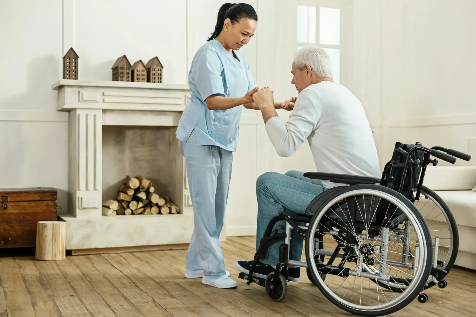Aide-soignante aidant un homme âgé à se lever de son fauteuil roulant
